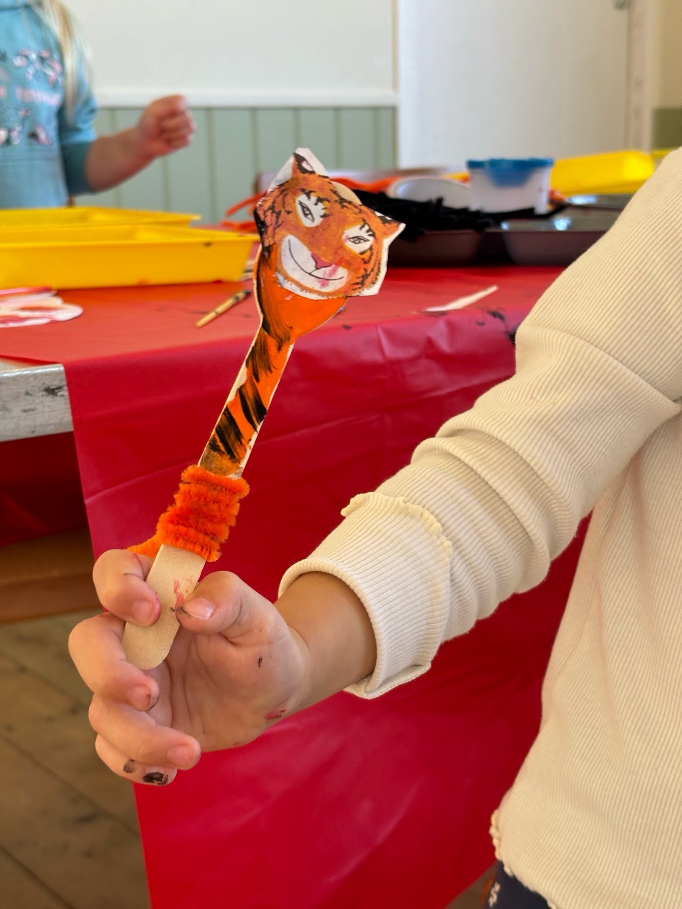 Child holding a handmade tiger puppet at Happy Little Makers